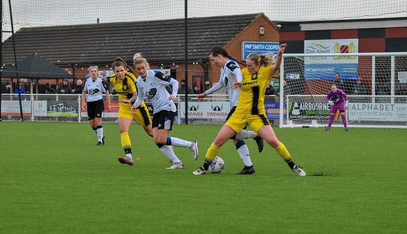 Emmalee Hornsby (Brewers player on left) watches on as forward Ella Ritchie goes in for a challenge against Derby County